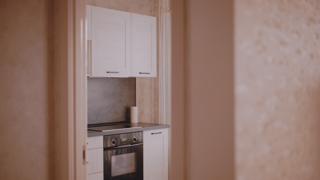 Lady walking toward kitchen with long hair visible from behind as doorway reveals bright interior of home creating warm domestic atmosphere of everyday routine lifestyle