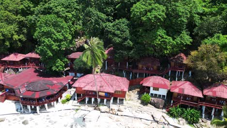 Island-Hill-Huts-in-lush-Jungle-fores,-emerald-waters-lagoon