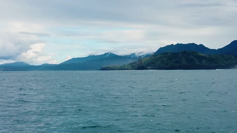 HD-120fps-Hawaii-Kauai-Bootfahren-Auf-Dem-Ozean,-Von-Rechts-Nach-Links-Schwebend,-Grüne-Hügel-Und-Berge-In-Der-Ferne-Mit-Viel-Bootsgischt