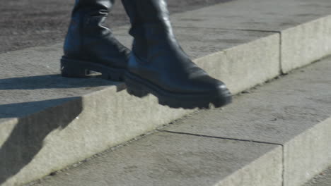 black woman's boots walking down grey stone steps