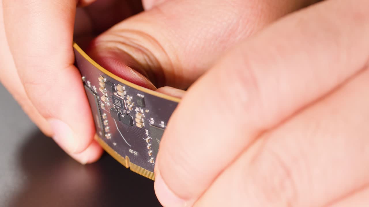 Macro di mani che piegano un moderno circuito elettronico flessibile sotto le luci di uno studio