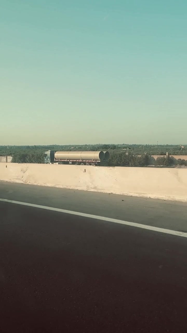Un grande camion cisterna che percorre un'autostrada con campi verdi e alberi, ripresa ravvicinata.
