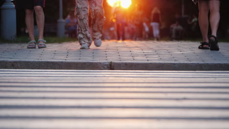 People-Walk-In-The-Evening-City-At-Sunset-In-The-Frame-You-Can-See-The-Man\'s-Togas-In-Camouflage-Pan