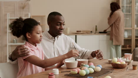 father and daughter painting easter eggs