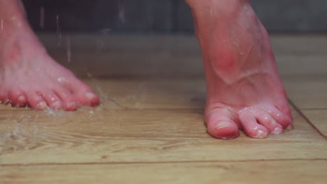 close up partial view of woman bathing in modern tiled shower, hand applying water to leg, water dripping past ankle onto floor, showcasing intimate self care moment in spa environment