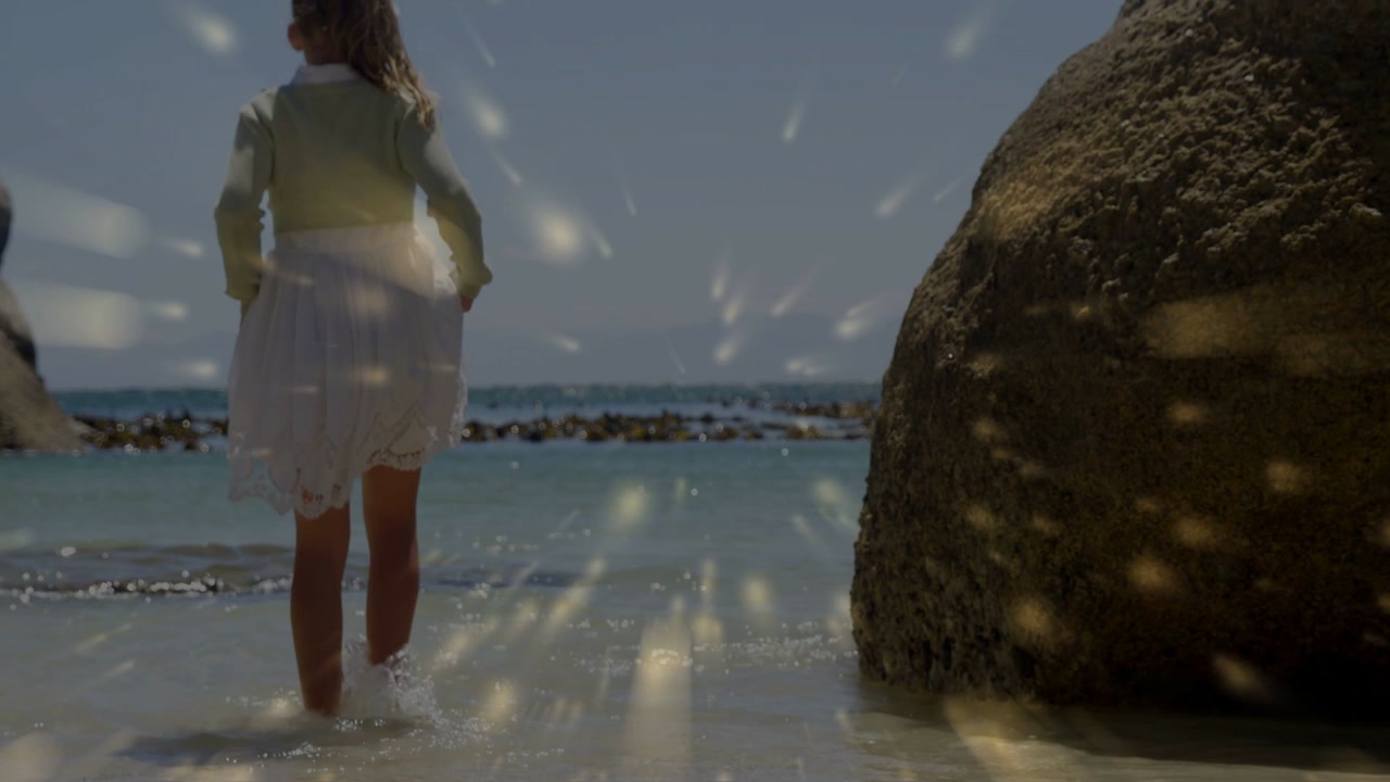 Girl stepping into shallow surf at beach cove, lifting skirt, golden light guiding travel stories