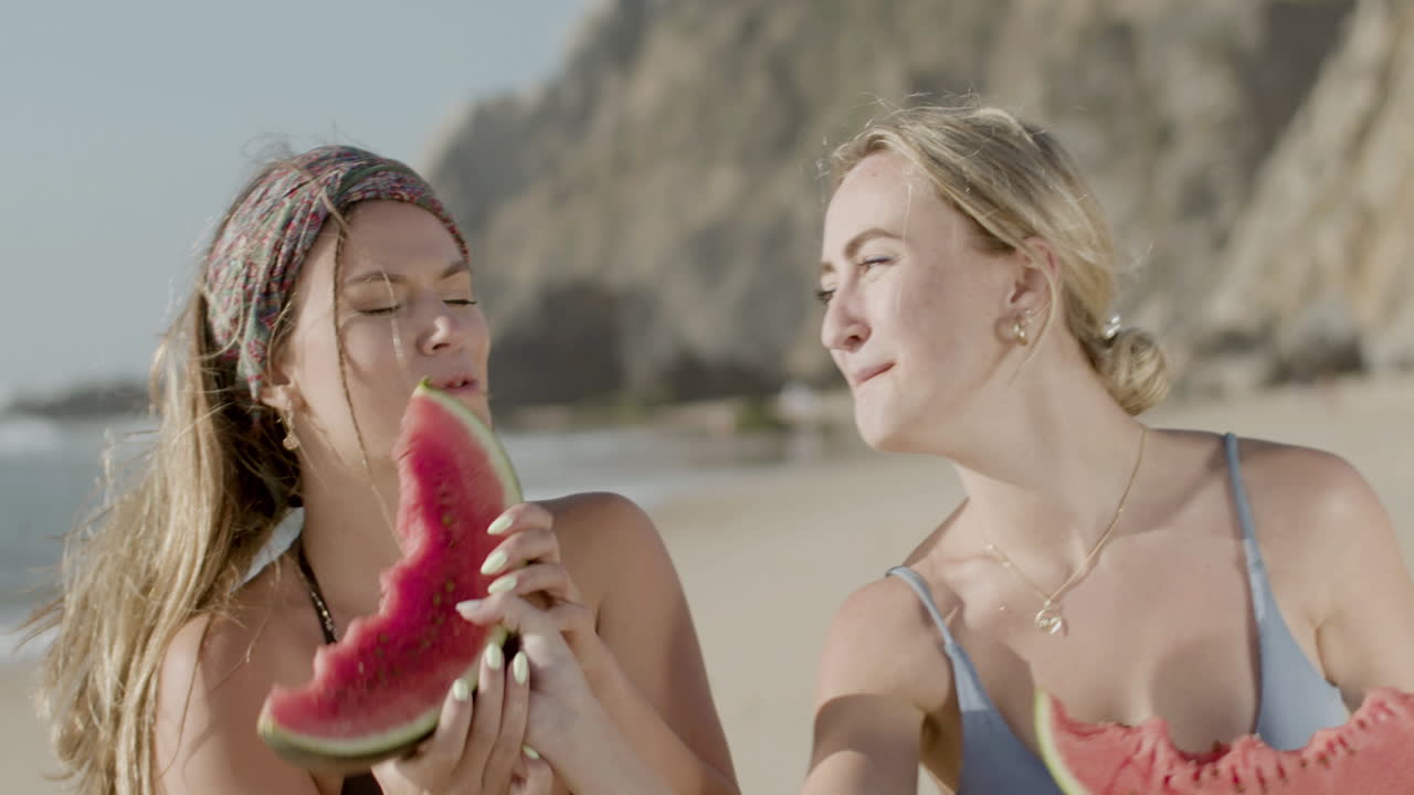 해변에서 수박을 먹으며 즐거움을 느끼는 친구들의 전면 전망