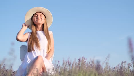 a happy smiling girl in a hat is contentedly sitting in a lavender field young girl in lavender fields on a sunny day in the countryside pretty woman sitting on lavender field at sunny day