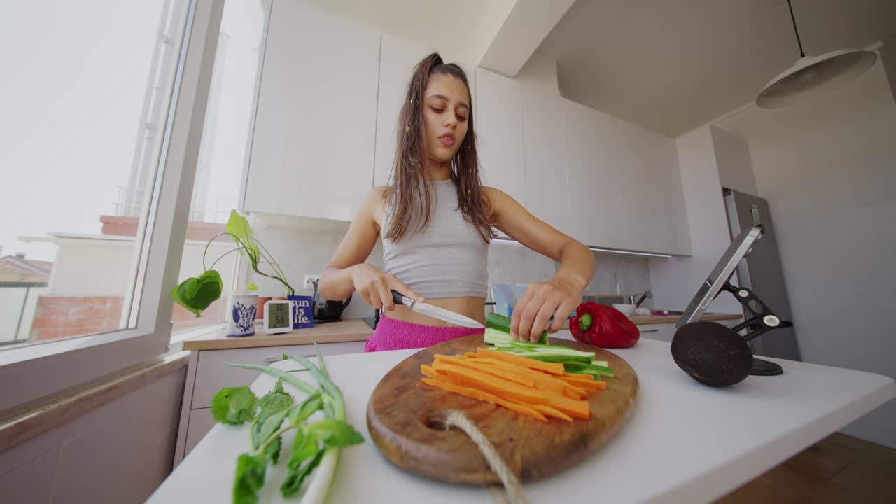 Mujer joven preparando verduras en una cocina para una comida saludable