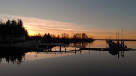 Drohnen-4K-Aufnahmen-Der-Historischen-Stewart-Farm,-Tief-Fliegender-Dunkler-Und-Mysteriöser-Sonnenuntergang-über-Tiefem-Wasser,-Der-Nach-Links-Entlang-Einer-Bootsanlegebrücke-In-Einem-Yachthafen-Schwenkt