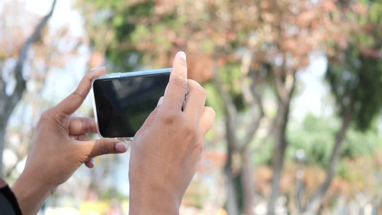 una mujer tomando una foto con su teléfono en un parque