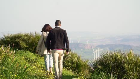 slow motion shot of couple hiking in high rural place near windmills