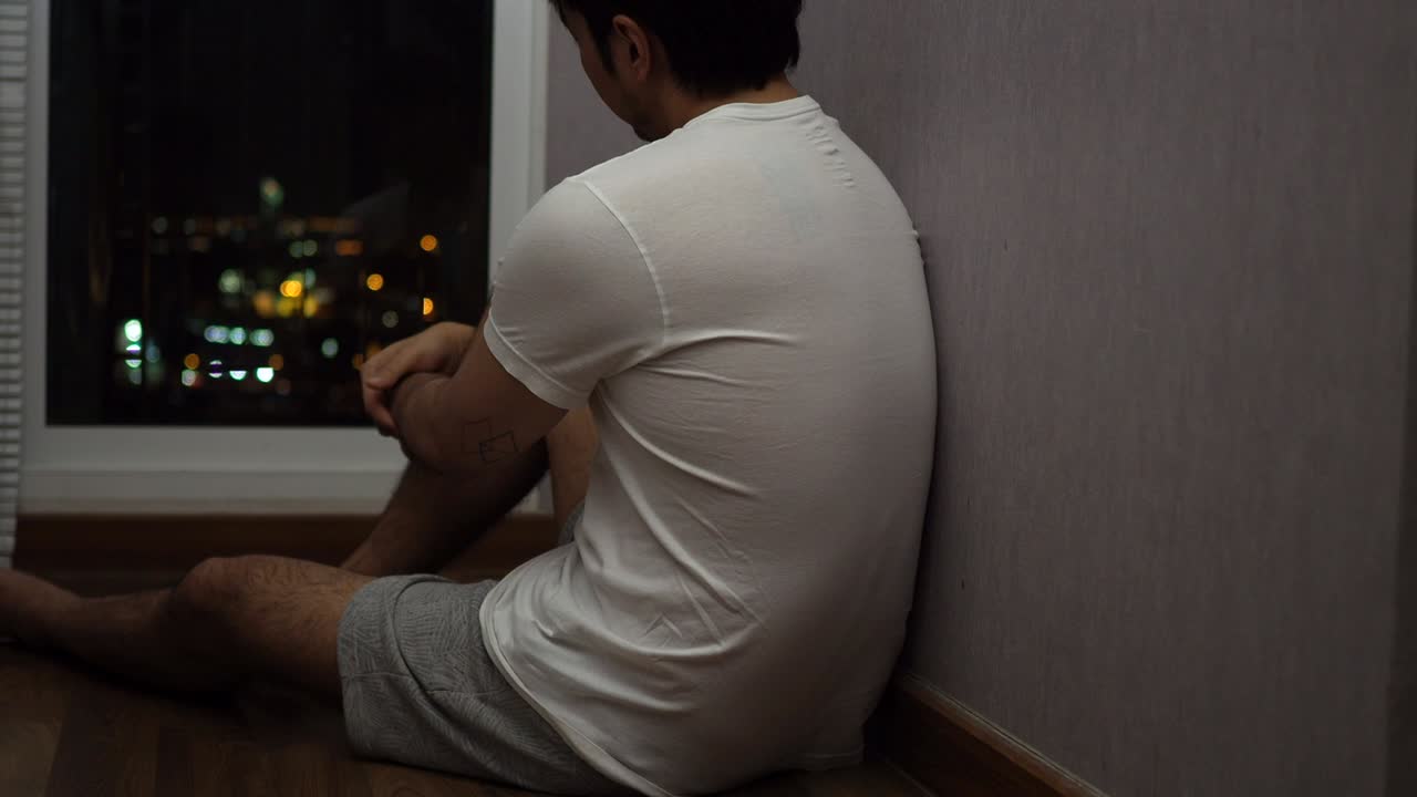 창문 에 앉아 있는 남자, 밤에는 우울하고 슬프게 보입니다.