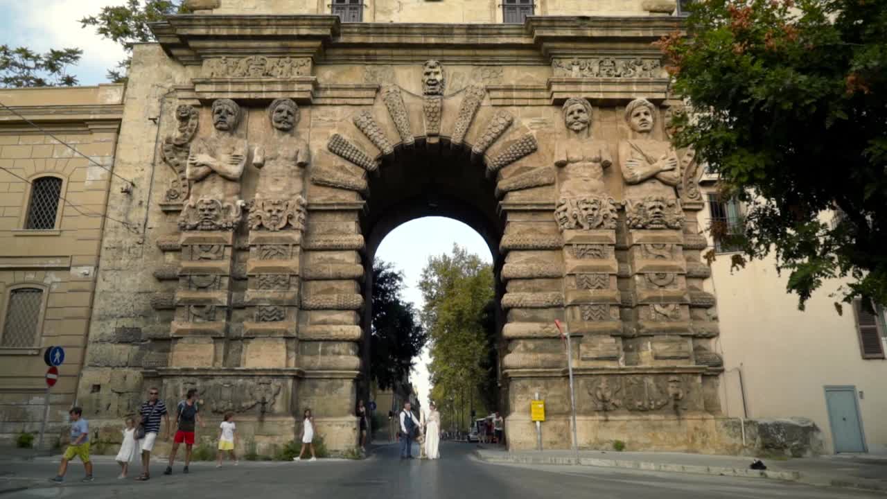 una pareja de bodas caminando por un antiguo arco en una ciudad italiana.