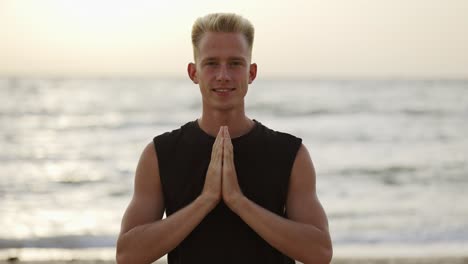 portrait of a young man who practices yoga on a sports mat at dawn. performing a specific exercise. meditation, hands. free time, rest