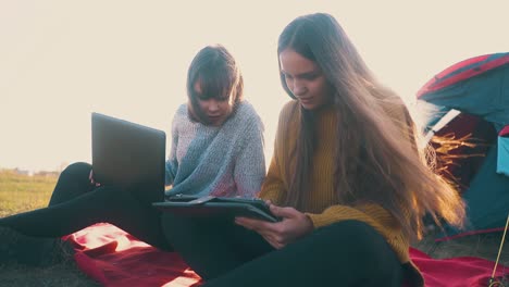 mujeres con tabletas y computadoras portátiles en un cómodo campamento