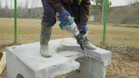 male worker builder uses electric impact drill to demolish precast concrete pits well slow motion