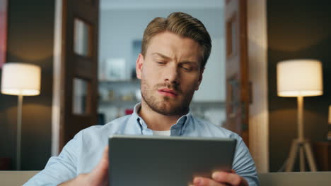 Focused man reading pad computer zoom out. Serious businessman zooming screen