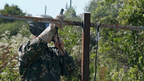 slow motion man finishes welding of fence and checks result