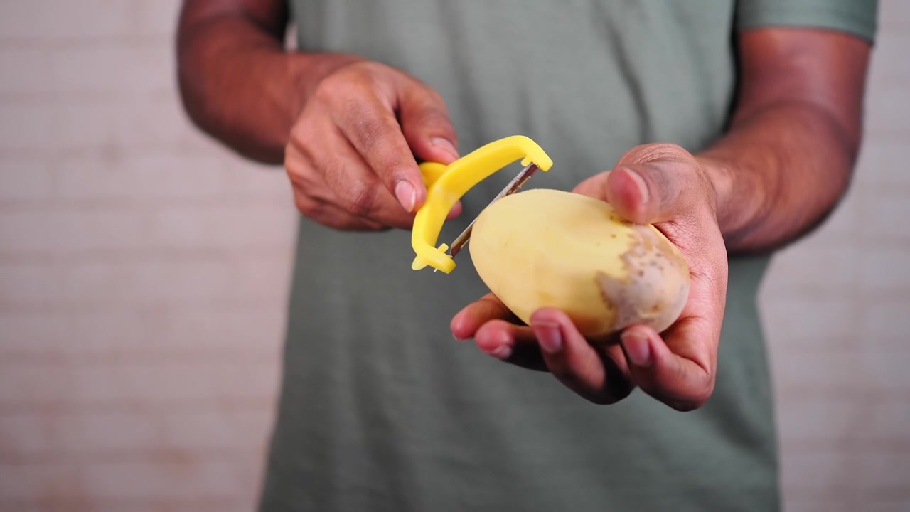 Person Peeling a Potato with a Yellow Vegetable Peeler