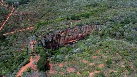 drone aérien tournant un plan large de la grande entrée de la grotte de lapa doce de roches colorées avec une forêt tropicale autonome en dessous dans le parc national de la chapada diamantina à bahia, au nord-est du brésil