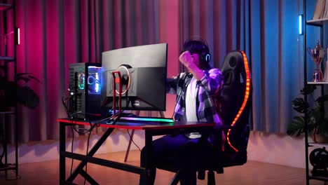 excited asian teen boy gamer celebrates victory while playing video game on computer