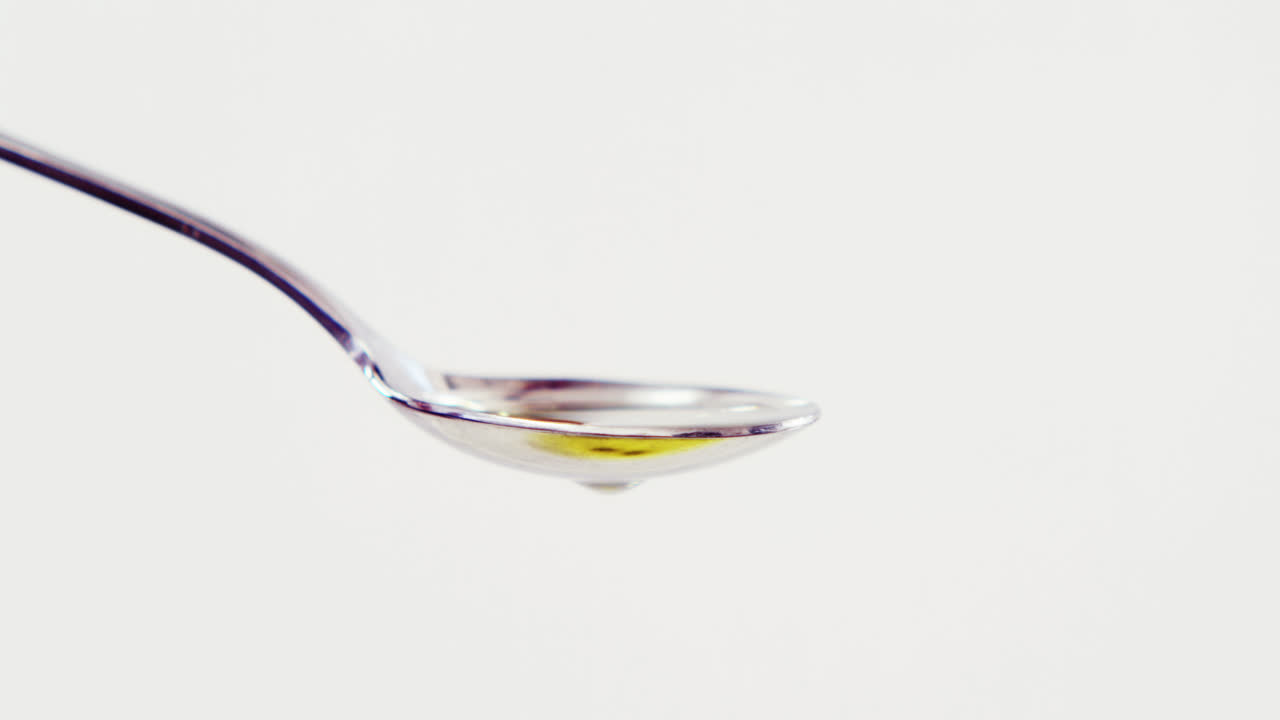 cereza roja cayendo en la cuchara con aceite de oliva