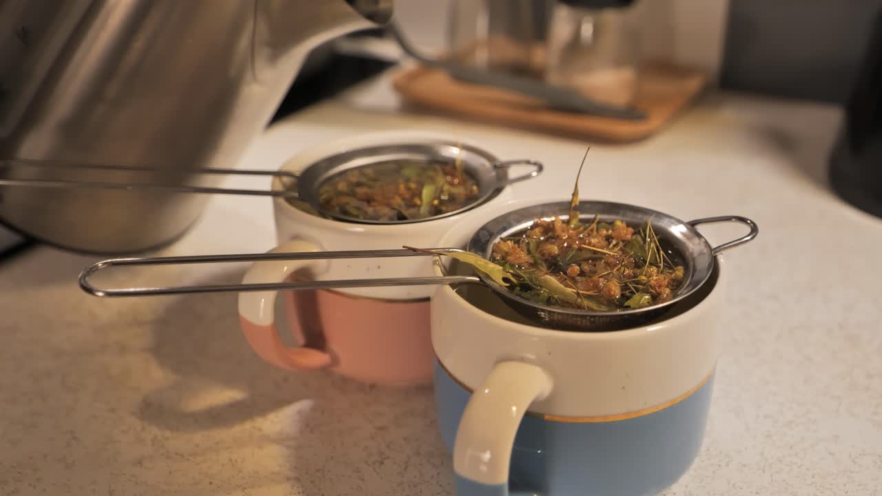 Hot water poured into a tea strainer over herbs - 4K.