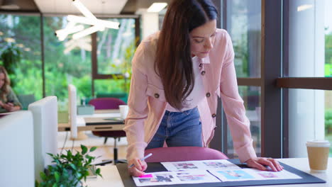 Mujer-De-Negocios-Parada-Frente-Al-Escritorio-En-La-Oficina-Aprobando-O-Revisando-Pruebas-O-Diseños-De-Diseño.