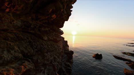 fpv drone flying through a gorge to reveal the sunset over the water