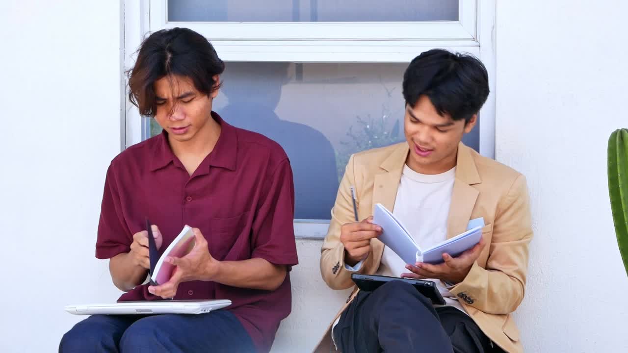 Confident asian students collaborating on homework in yard