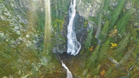 overhead view of majestic waterfalls with sunrays in wild forest of sweden during sunset