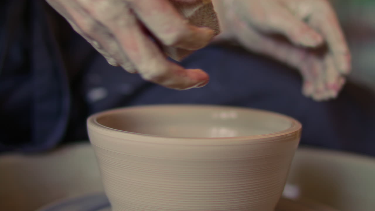Hands of Craftswoman Shaping Ceramic Bowl with Sponge on Pottery Wheel