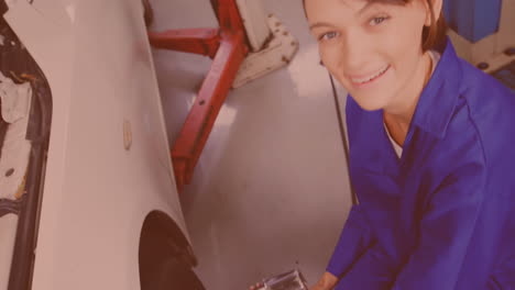 caucasian female mechanic screwing wheel of a car by pneumatic wrench at repair service station