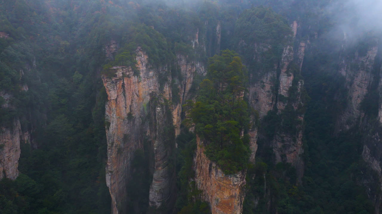 Nuvole basse e nebbia avvolgevano gli imponenti pilastri del Parco Forestale Nazionale di Zhangjiajie in Cina. Ripresa aerea.