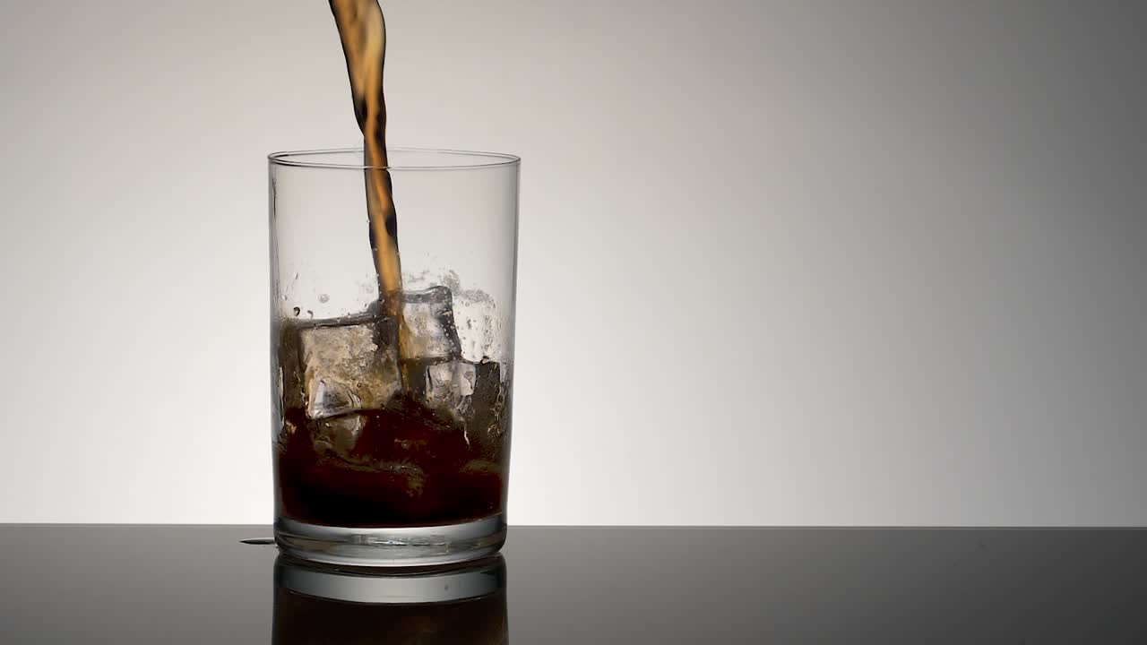 bebida a cámara lenta que se vierte en un vaso con cubitos de hielo