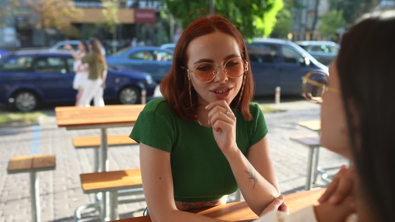 dos amigas que tienen una conversación al aire libre en un café