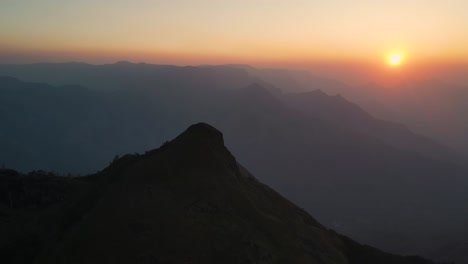 aerial drone shot of kolukkumalai range, wrapped in morning mist with sunlight breaking through