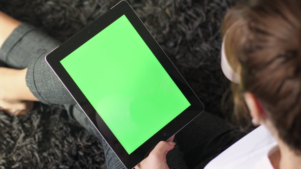 여성은 녹색 화면을 가진 디지털 태블릿을 사용합니다.