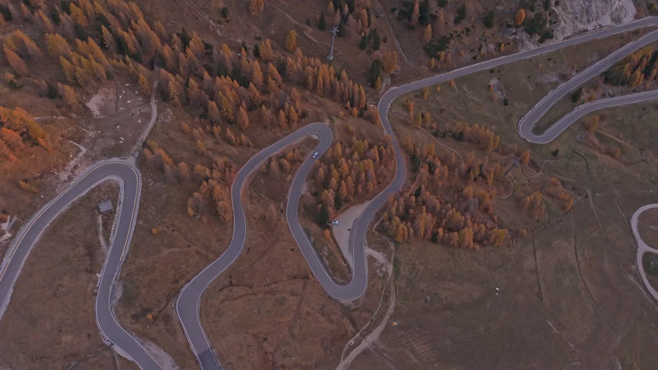 Aerial of cars driving on Passo Gardena at sunrise, Dolomites, Italy