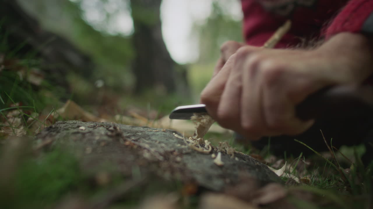 Hands of Man Feathering Wood with Knife for Making Fire in Forest