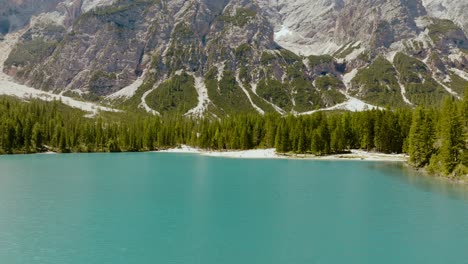 toma aérea de un dron sobre el río y el bosque con los alpes dolomitas en la parte de atrás, lago di braies, italia, dolomitas