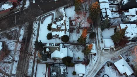 1-2 aerial pan out birds eye view over winter urban luxury home during a sunset tree tip lit branches with wet snowy slushed roads light traffic in a rich residential community with curvy sideroads