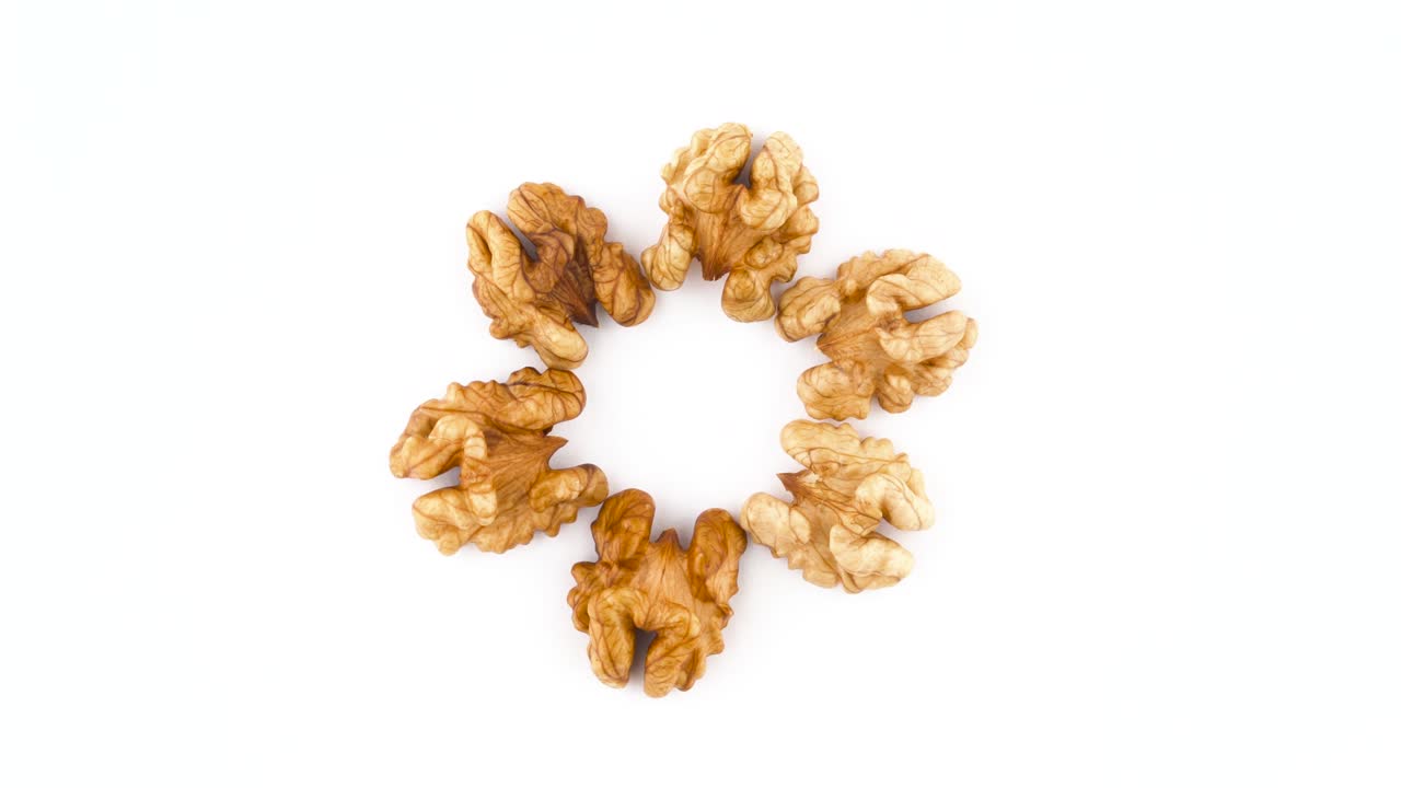 Top view from above of a circle shaped walnuts without the shell. Rotating on the turntable isolated on the white background. Close-up. Macro.
