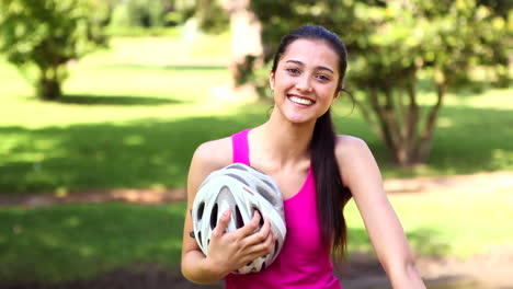 Fit-girl-taking-off-her-bike-helmet-smiling-at-camera