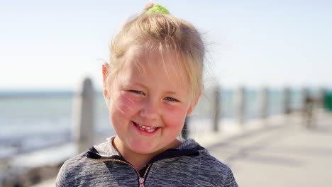 child, smile and shy face while at a beach