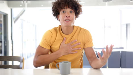 speaking passionately, man in yellow shirt gesturing with hands at home table