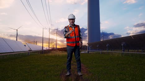 full body of angry asian male engineer with safety helmet shouting at someone while standing with solar panel and wind turbines