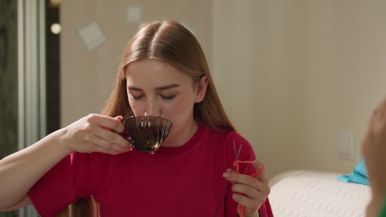 Jóvenes adultos relajados bebiendo bebidas calientes, reunión informal de adolescentes con bebidas calientes en un sofá acogedor, encuentro amistoso de jóvenes disfrutando de bebidas humeantes mientras descansan cómodamente en un sofá
