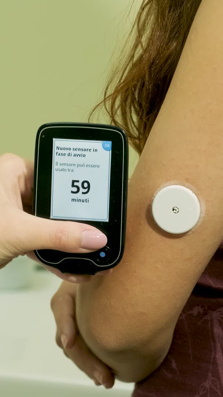 Close-up of Hand Scanning Continuous Glucose Monitor Sensor on Arm